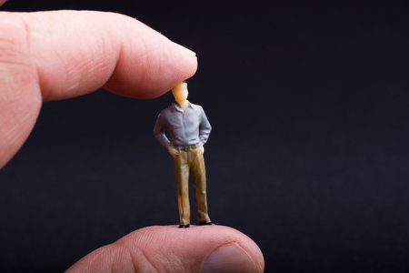 Hand holding figurine with black background.の写真素材