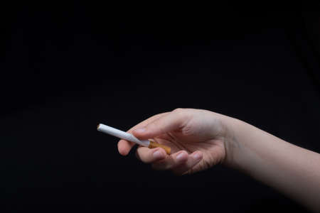 Hand is holding a cigarette on black backgroundの写真素材