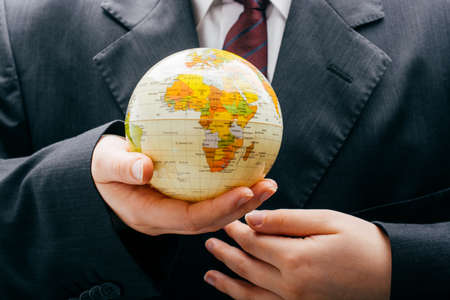Businessman is standing with an earth globe fot business conceptの写真素材