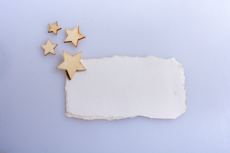 Little wooden stars placed on torn paper on whiteの写真素材