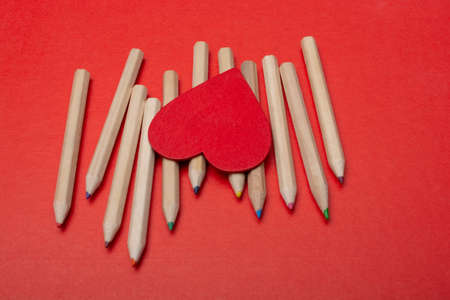 Heart icon and  multi-colored pencils on red backgroundの写真素材