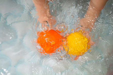 Child splashing water and plying with ballsの写真素材