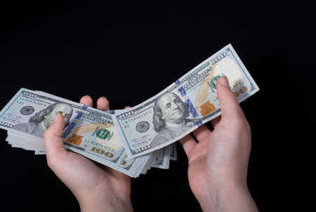 Hand holding American dollar banknotes on blackの写真素材