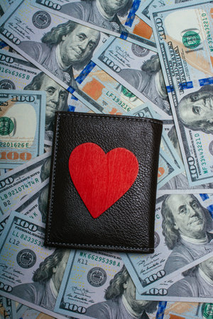 Red heart and wallet on dollar bills.  Concept of selling love for money