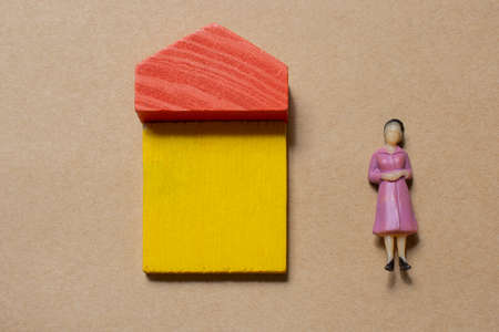 Woman figurine by House from wooden blocks as concept of buying, selling, renting real estate, building and  eco styleの写真素材