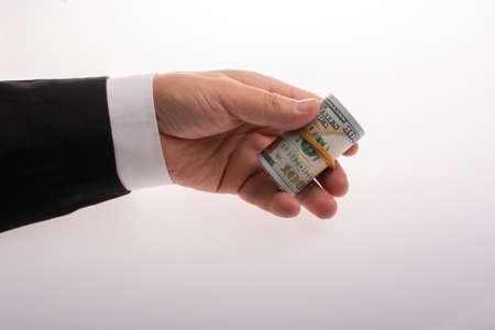 A man holds in his hand Money (US dollars) in a roll tied with a bandの写真素材