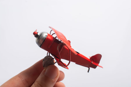 Hand holding a red toy plane on a white background