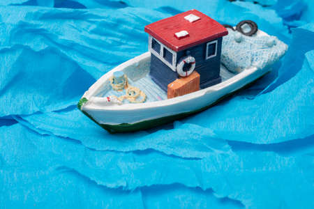 Little colorful model fishing boat placed on bloe paperの写真素材