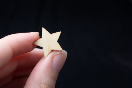 The hand holding a  wooden star.の写真素材
