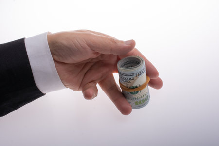 A man holds in his hand Money (US dollars) in a roll tied with a bandの写真素材