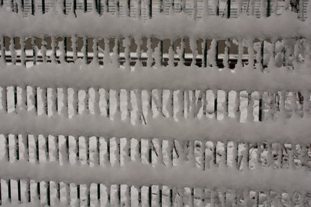 Winter cold snow on wire fence background.の写真素材