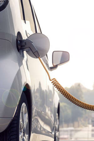 3d rendering of Electric car or vehicle at charging station charges battery with cable or charger for ecological range and sustainable energyの写真素材