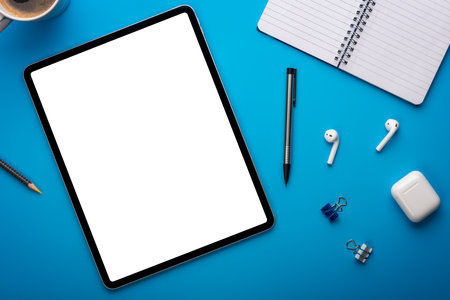 Notebook and Tablet Computer on Blue Desk or background laying flat on Creative workplace as mockup or Template with empty or blank page or screenの写真素材