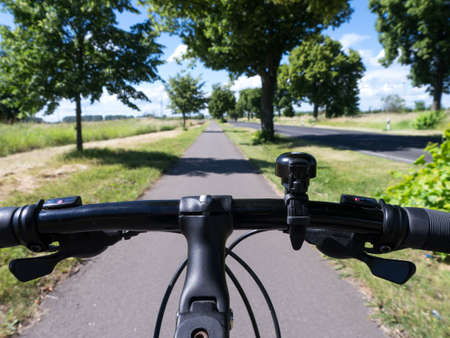 bicycle tour on a way in landscape with green treesの写真素材