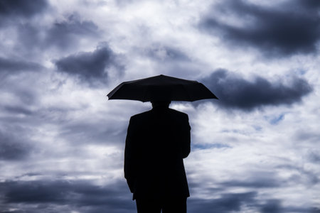 businessman holind an umbrella and stormy clouds