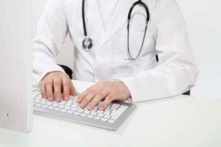 doctor typing on computer in doctor's officeの写真素材