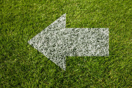arrow pointing to the left on green grassの写真素材