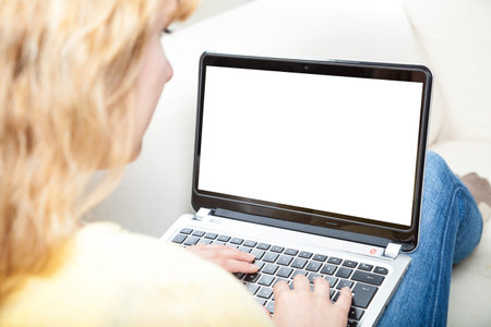 blond woman sittin on sofa typing on laptop (whitespace)