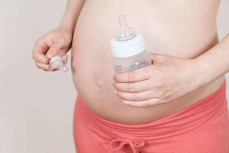 Pregnant holding pacifier and bottle