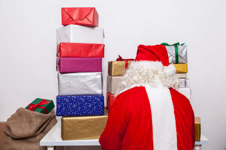 Santa wraps christmas presents at deskの写真素材
