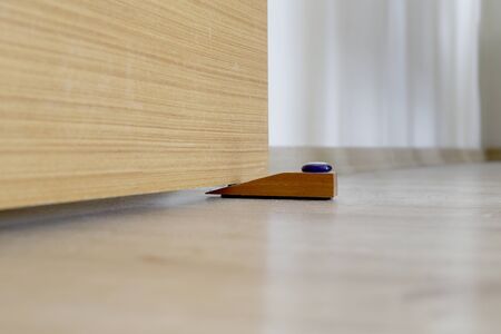 Close-up elements of the interior of the apartment. Wooden chrome door stopper on laminate floorの写真素材