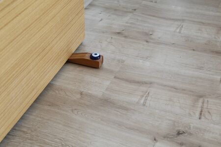 Close-up elements of the interior of the apartment. Wooden chrome door stopper on laminate floorの写真素材