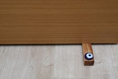 Close-up elements of the interior of the apartment. Wooden chrome door stopper on laminate floorの写真素材