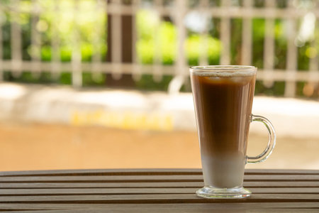 Closeup one glass with ice latte on wooden table. Selective focus