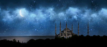 Istanbul Turkey. Sultan Ahmet Mosque named Blue Mosque. Front view of crescent shaped moon and mosque in front of night cloudy and starry sky. ramadan, the holy month of muslims. selective focusの写真素材