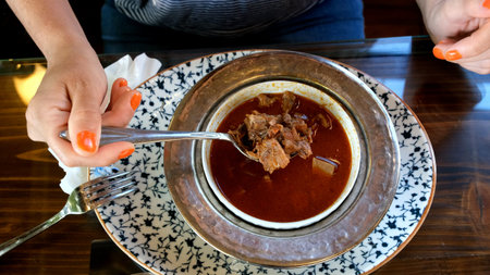 female customer drinking kelle paca soup in restaurant