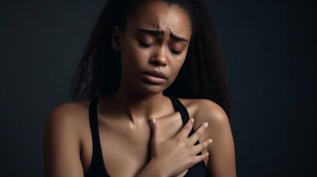 Young black woman pressing on chest with painful expression. Severe heartache, having heart attack or painful cramps, heart diseaseの素材
