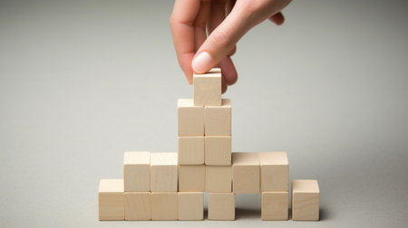 Hand arranging wood block stacking as step stair on gray background, business growth conceptの素材