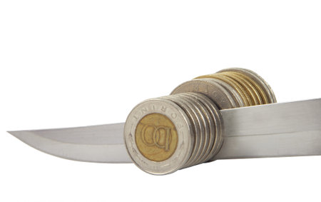 Knife cuting a pile of coin. Concept of money reduction, budget cuts, recession