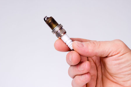 Hand man holding a used spark plug on white background
