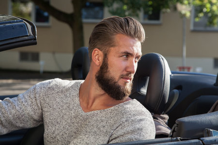 Young businessman is driving in luxury cabriolet car
