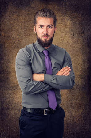 Bearded businessman with his arms crossed over isolated, brown backgroundの写真素材