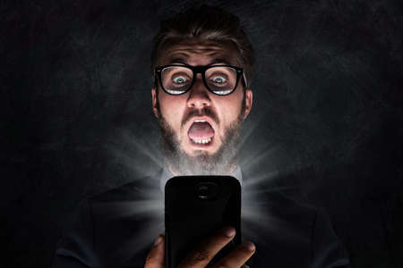 Nerd with glasses is shocked after reading a textの写真素材