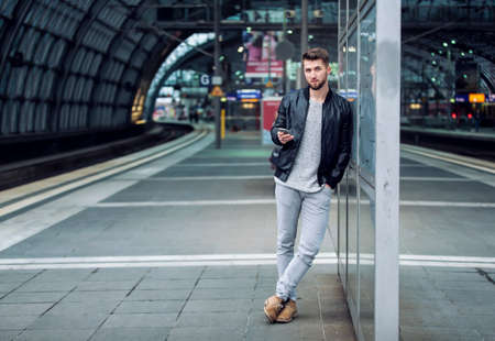 Attractive man with a beard is waiting at the train stationの写真素材