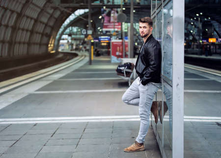 Attractive man with a beard is waiting at the train stationの写真素材
