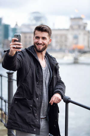 Attractive man with a beard is taking a selfie in front of the Berlin Reichstagの写真素材