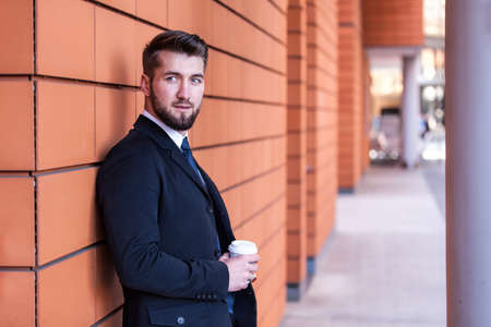 Attractive business man leaning on a wall in the cityの写真素材