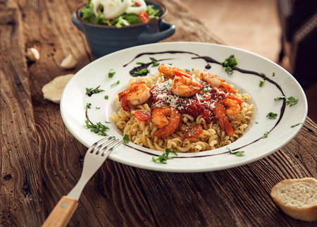 Pasta with tomato sauce and shrimp on a wooden tableの写真素材