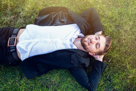 Attractive man with a beard is lying in the parkの写真素材