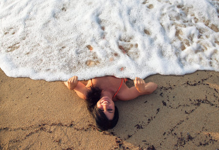 Attractive woman is lying under a cover of sea foam
