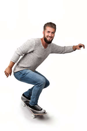 Attractive young man with a beard has fun on a skate boardの写真素材