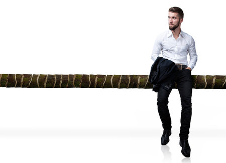 Attractive business man is sitting on a bamboo railing