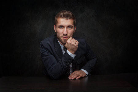 Attractive businessman is sitting in front of a black backgroundの写真素材