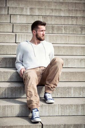Attractive man with a beard is relaxing on the stepsの写真素材
