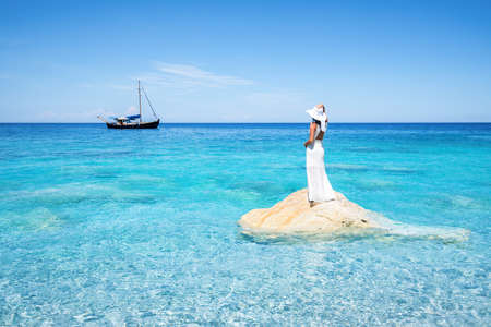 Beautiful woman in a white dress is looking at the beachの写真素材