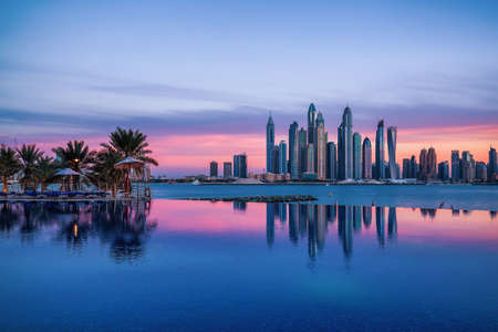 Panorama of Dubai Marina at sunset with a swimming pool in front